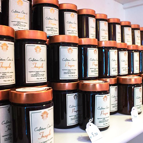 File di vasetti di confettura extra Aldemorisco con capsula di rame ed etichetta scritta a mano: fragola, prugna, albicocca