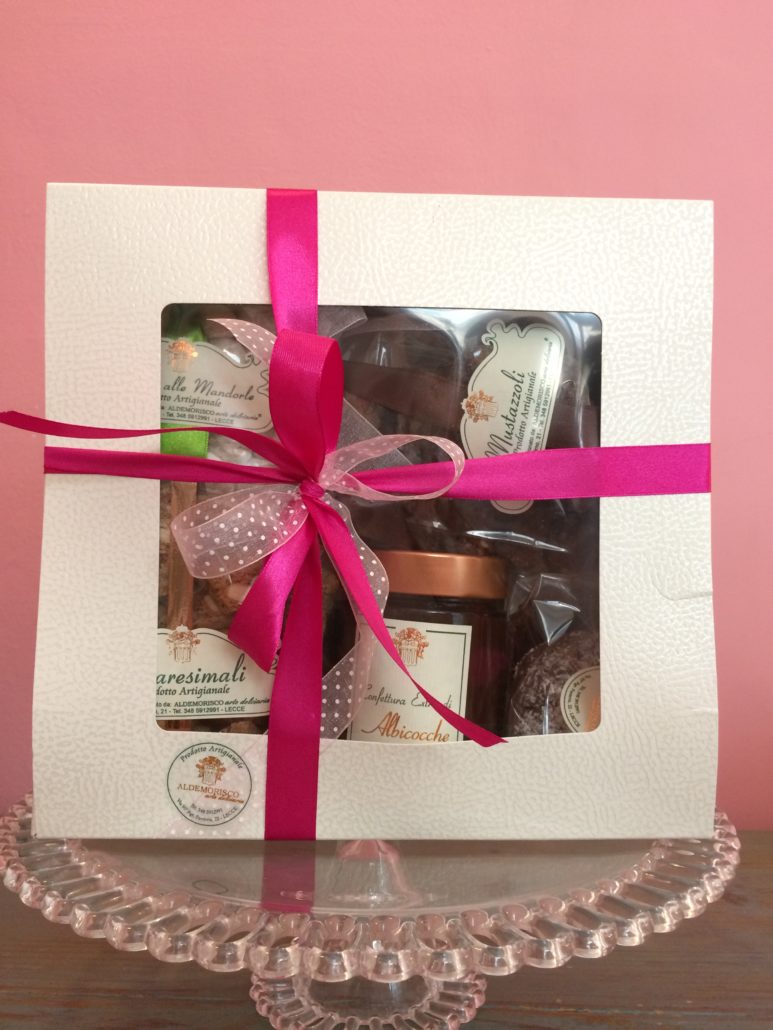 Scatola regalo Aldemorisco con finestra e nastro fucsia, dentro mustazzoli, quaresimali, pasta di mandorle e un vasetto di confettura di albicocche
