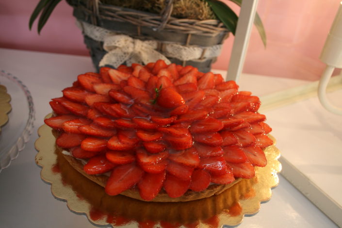Crostata ricoperta di fragole fresche tagliate e lucidate, sul vassoio dorato