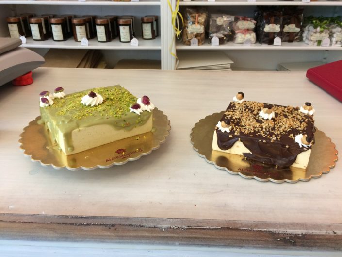 Due semifreddi Aldemorisco sul vassoio dorato: uno al pistacchio con granella verde, uno al gianduia con nocciole tritate