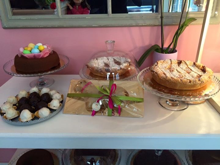 Torte fresche in negozio: torta al cioccolato con ovetti, pastiera spolverata di zucchero a velo e crostata di frutta su alzate di vetro